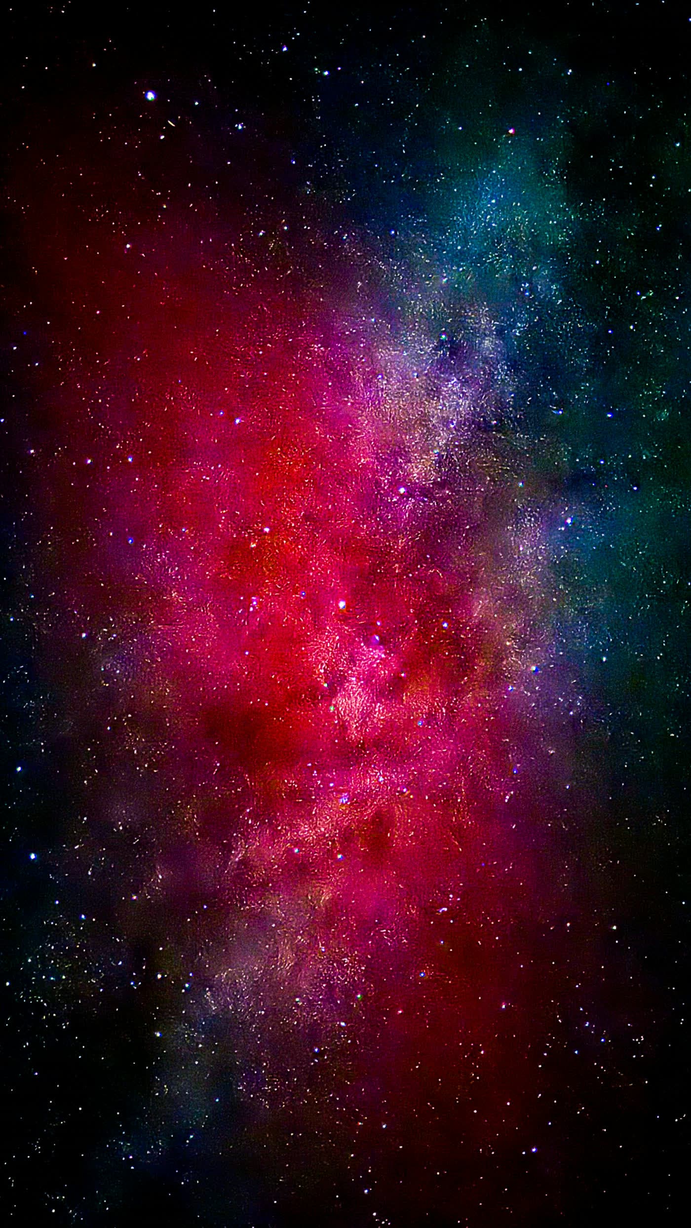 The Milky Way overhead, a crimson and teal band of stars filling the frame.